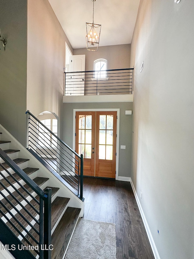 foyer entrance featuring dark hardwood / wood-style floors, a chandelier, a high ceiling, and french doors