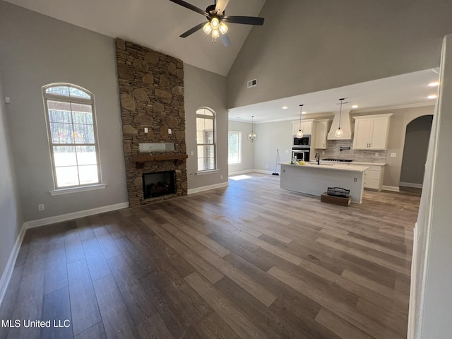 145 Poplar Ln, Holly Springs, MS 38635 - unfurnished living room featuring ceiling fan, arched walkways, baseboards, a sink, and high vaulted ceiling