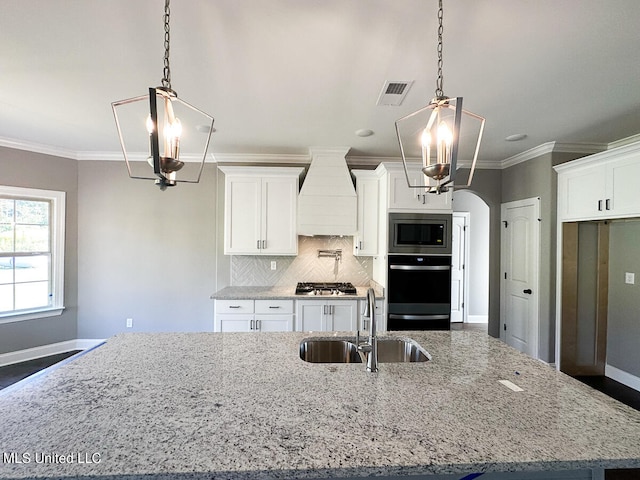 kitchen with white cabinetry, sink, premium range hood, pendant lighting, and appliances with stainless steel finishes