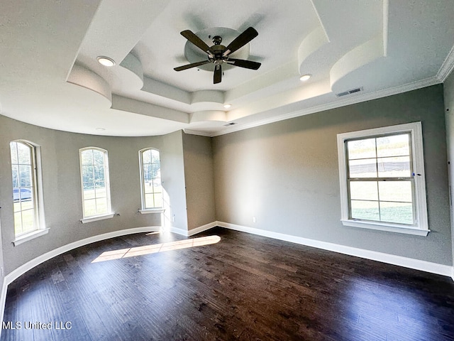 empty room with a tray ceiling, ceiling fan, wood-type flooring, and ornamental molding