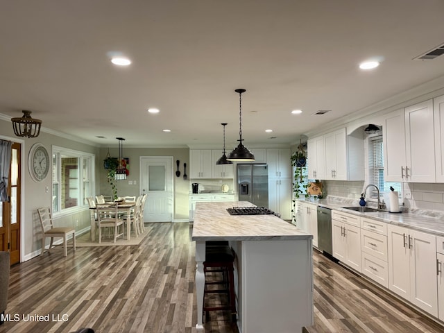 kitchen with crown molding, light countertops, appliances with stainless steel finishes, white cabinets, and a sink