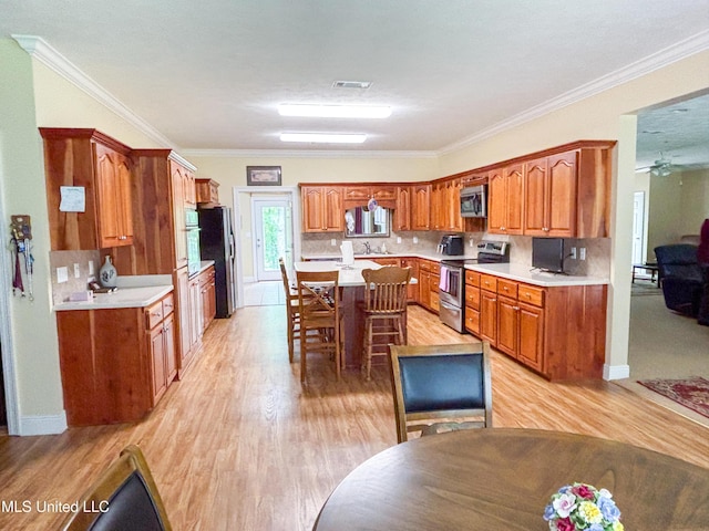 8855 Pine Springs Rd, Meridian, MS 39305 - kitchen with stainless steel appliances, brown cabinetry, light wood finished floors, light countertops, and ornamental molding