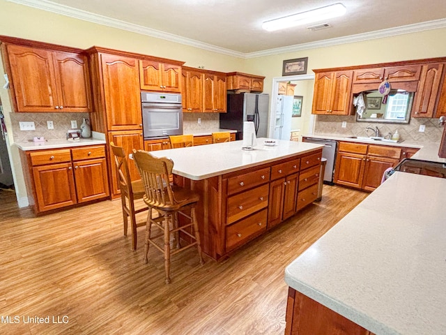 8855 Pine Springs Rd, Meridian, MS 39305 - kitchen with stainless steel appliances, a center island, tasteful backsplash, brown cabinetry, and crown molding