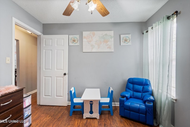 rec room featuring a textured ceiling, a healthy amount of sunlight, and dark wood-type flooring