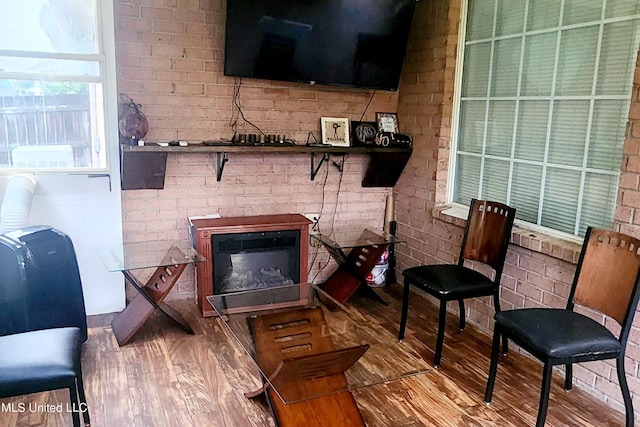 living room with hardwood / wood-style flooring and brick wall