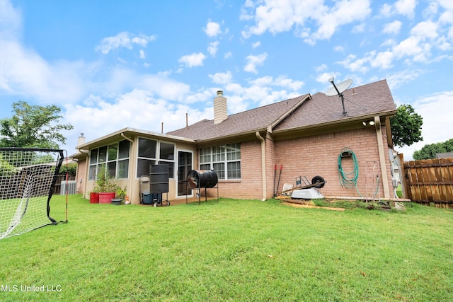 rear view of house with a yard, a sunroom, and central AC unit