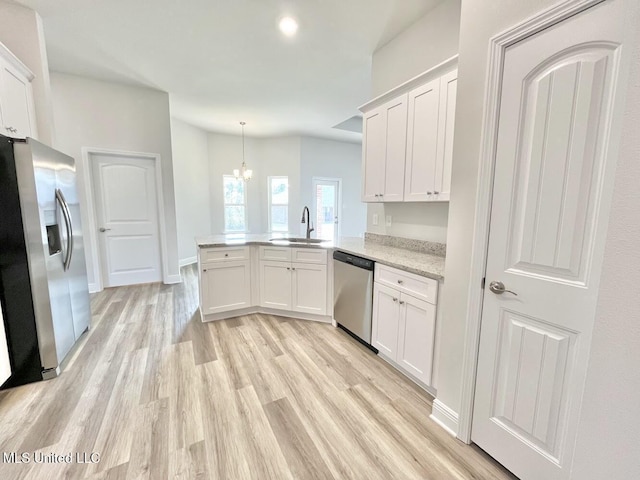 kitchen featuring light wood finished floors, a peninsula, white cabinets, a sink, and appliances with stainless steel finishes