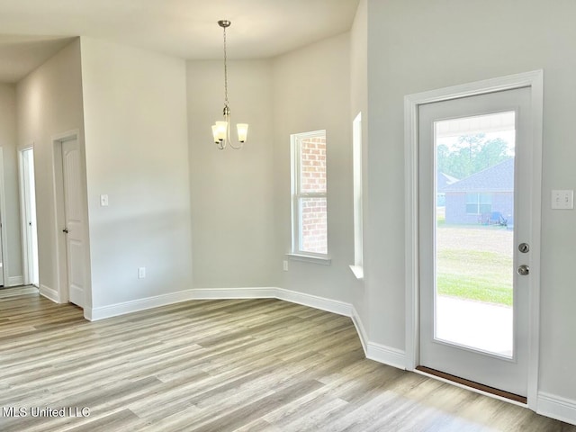 foyer featuring a high ceiling, light wood finished floors, baseboards, and a notable chandelier