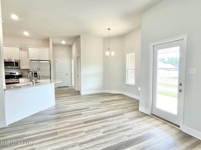 kitchen featuring white cabinets, light wood-type flooring, recessed lighting, a notable chandelier, and appliances with stainless steel finishes