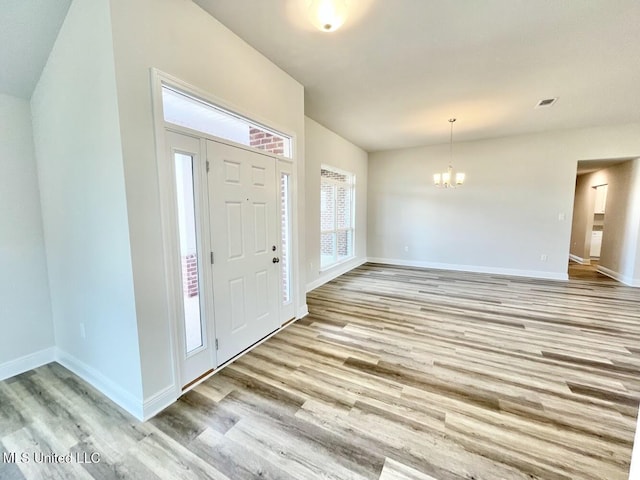 entrance foyer with light wood-style floors, visible vents, baseboards, and a notable chandelier