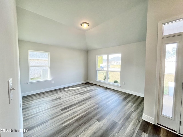 interior space with vaulted ceiling, wood finished floors, and baseboards