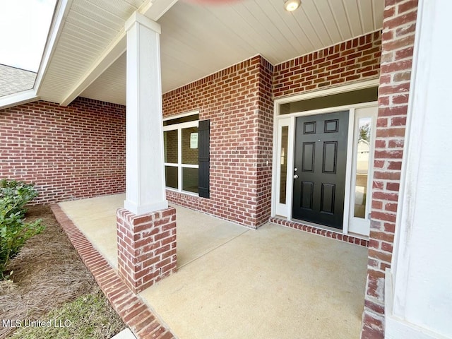 property entrance with covered porch and brick siding