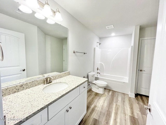 bathroom with wood finished floors, visible vents, toilet, vanity, and shower / bathing tub combination