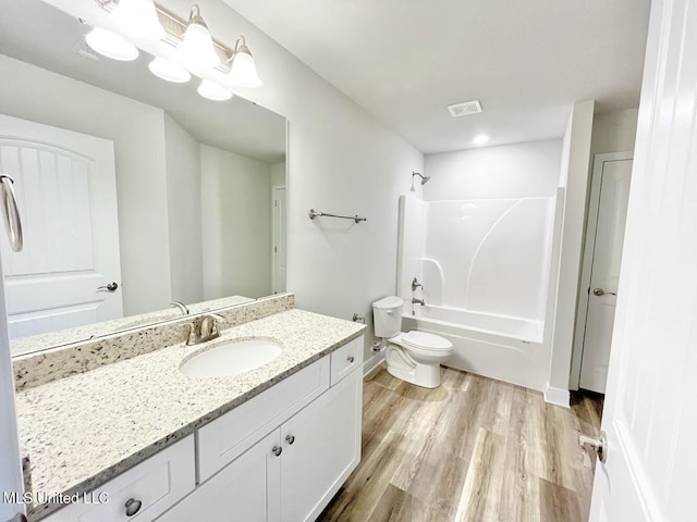 full bath with wood finished floors, vanity, washtub / shower combination, toilet, and visible vents
