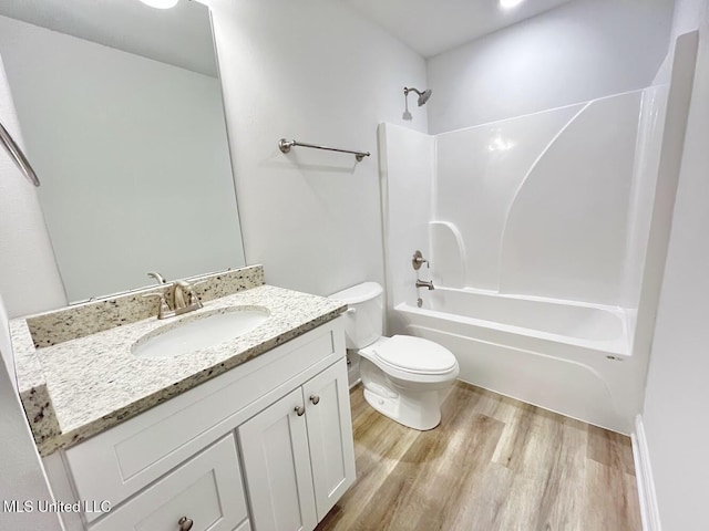 bathroom featuring toilet, vanity, wood finished floors, and shower / bathing tub combination