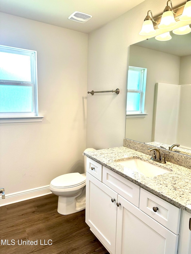 bathroom featuring a wealth of natural light, toilet, vanity, and hardwood / wood-style flooring