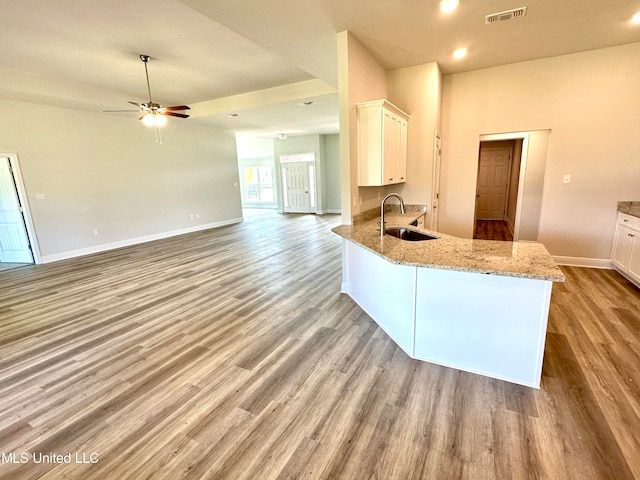 kitchen with kitchen peninsula, light stone counters, sink, light hardwood / wood-style flooring, and white cabinetry