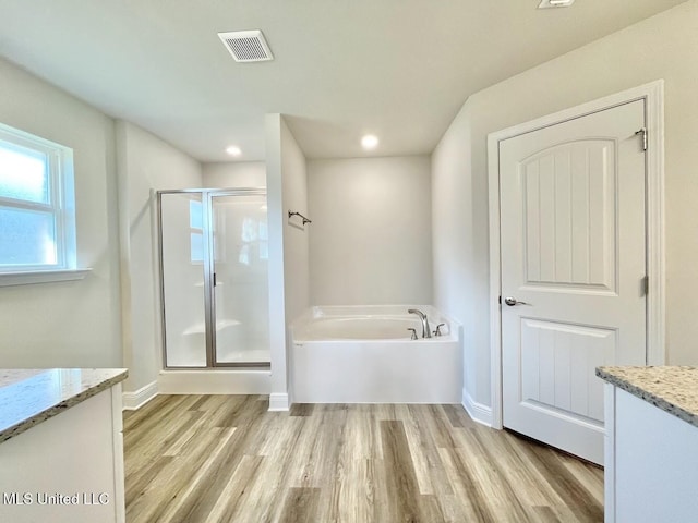 full bathroom featuring a garden tub, vanity, wood finished floors, and visible vents