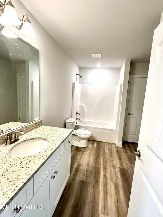 full bathroom featuring hardwood / wood-style floors, vanity,  shower combination, and toilet