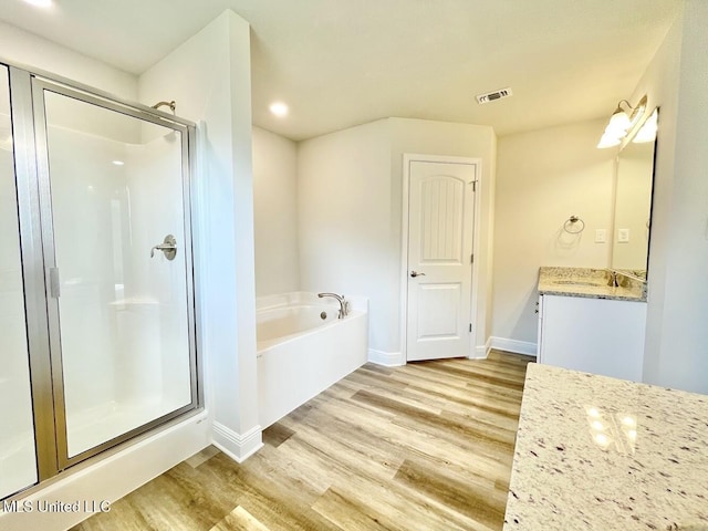 bathroom featuring a bath, a stall shower, visible vents, wood finished floors, and vanity