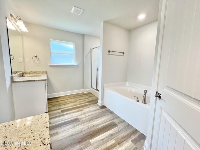 bathroom with a bath, a stall shower, visible vents, wood finished floors, and vanity