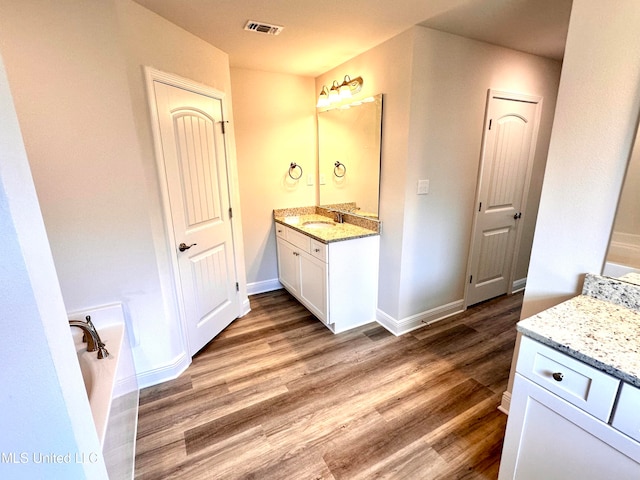 bathroom with vanity, a bath, and hardwood / wood-style flooring