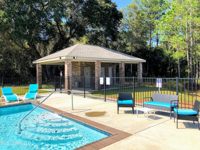 community pool with fence, a patio area, and an outdoor structure