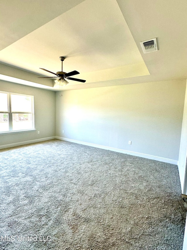 carpeted spare room featuring ceiling fan and a raised ceiling