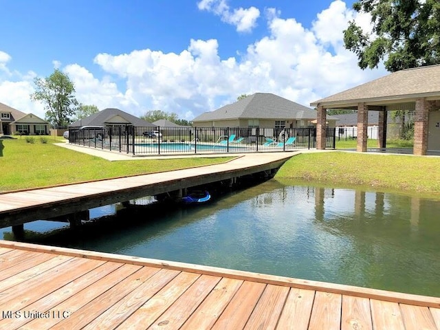 view of dock with fence, a lawn, a fenced in pool, and a water view