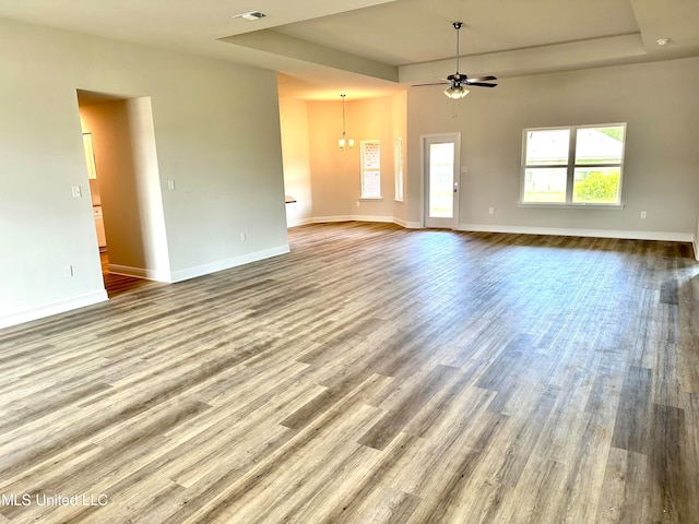 unfurnished living room with wood-type flooring and ceiling fan with notable chandelier