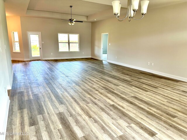 spare room with ceiling fan with notable chandelier and wood-type flooring