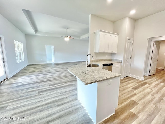 kitchen featuring white cabinets, baseboards, stainless steel dishwasher, and a sink