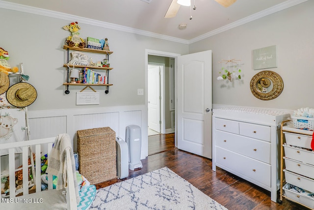 bedroom featuring crown molding, a crib, dark wood-type flooring, and ceiling fan