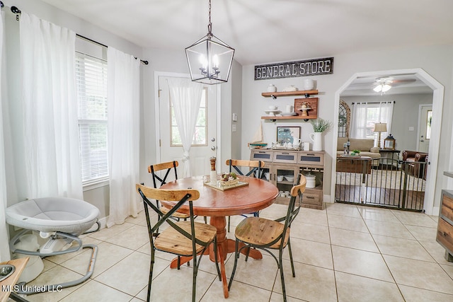 tiled dining area with ceiling fan with notable chandelier