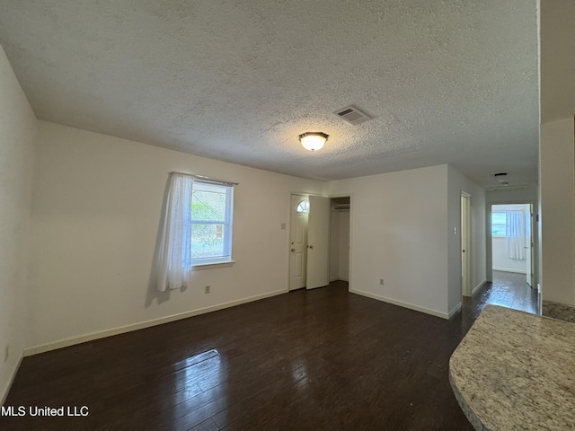 unfurnished room featuring dark hardwood / wood-style floors and a textured ceiling