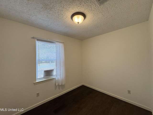 unfurnished room with dark wood-type flooring and a textured ceiling