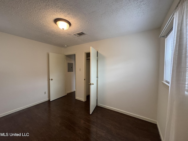 unfurnished bedroom featuring dark wood-type flooring, electric panel, and a textured ceiling