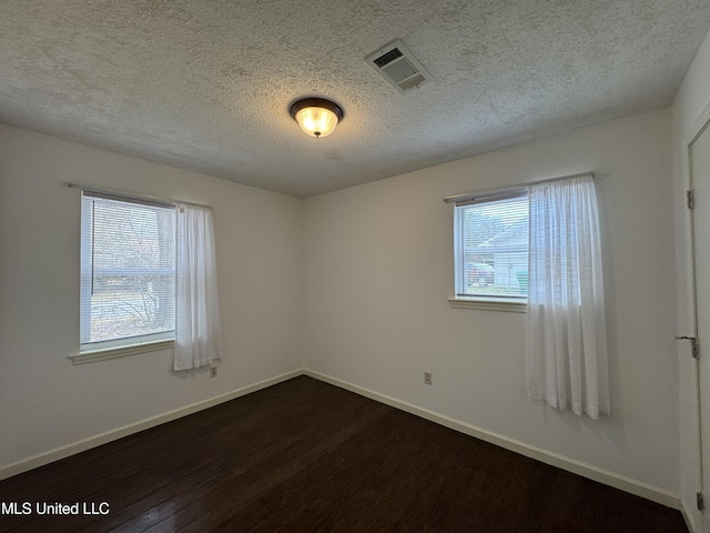 spare room with plenty of natural light, dark hardwood / wood-style floors, and a textured ceiling