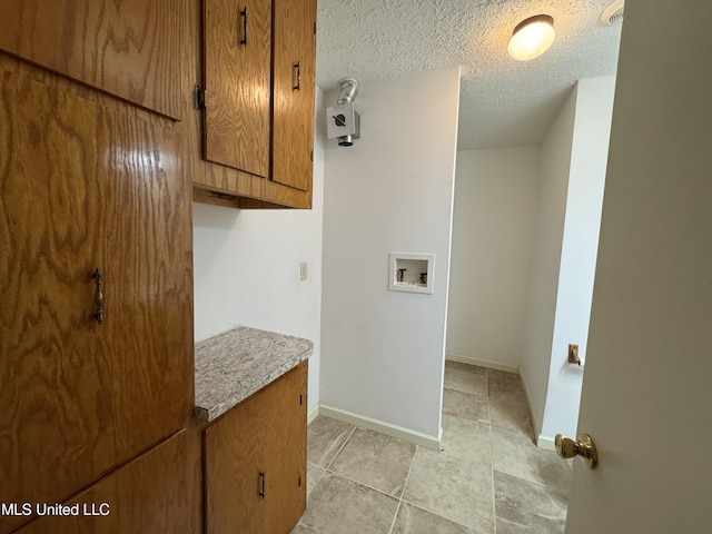 laundry area with washer hookup, cabinets, a textured ceiling, and light tile patterned flooring