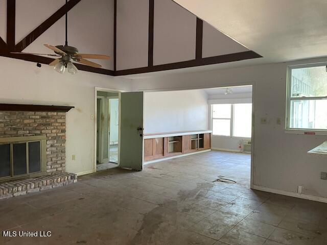 unfurnished living room featuring a brick fireplace, baseboards, high vaulted ceiling, and a ceiling fan