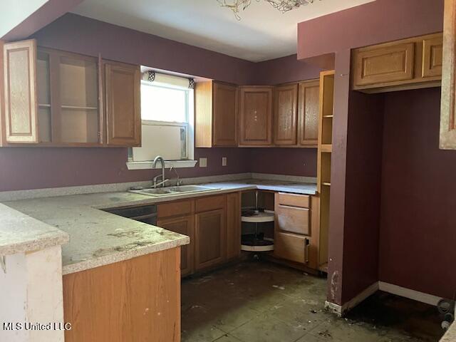 kitchen featuring a peninsula, light countertops, baseboards, and a sink