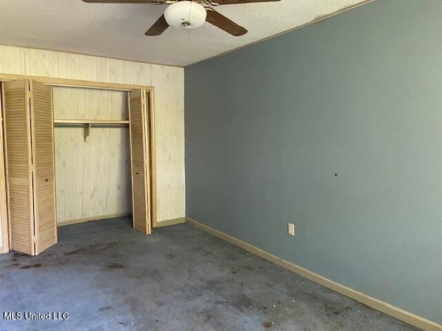 unfurnished bedroom featuring a closet, wooden walls, baseboards, and a ceiling fan
