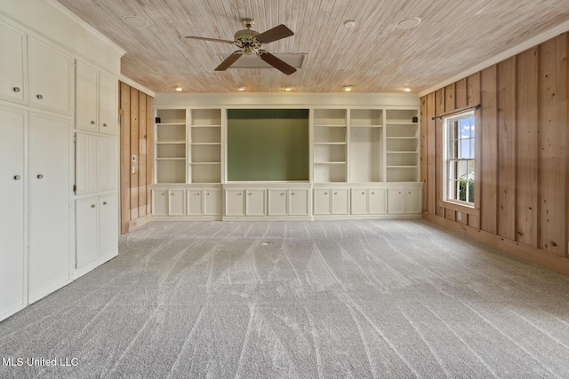 interior space featuring built in features, light colored carpet, wood walls, wood ceiling, and a ceiling fan