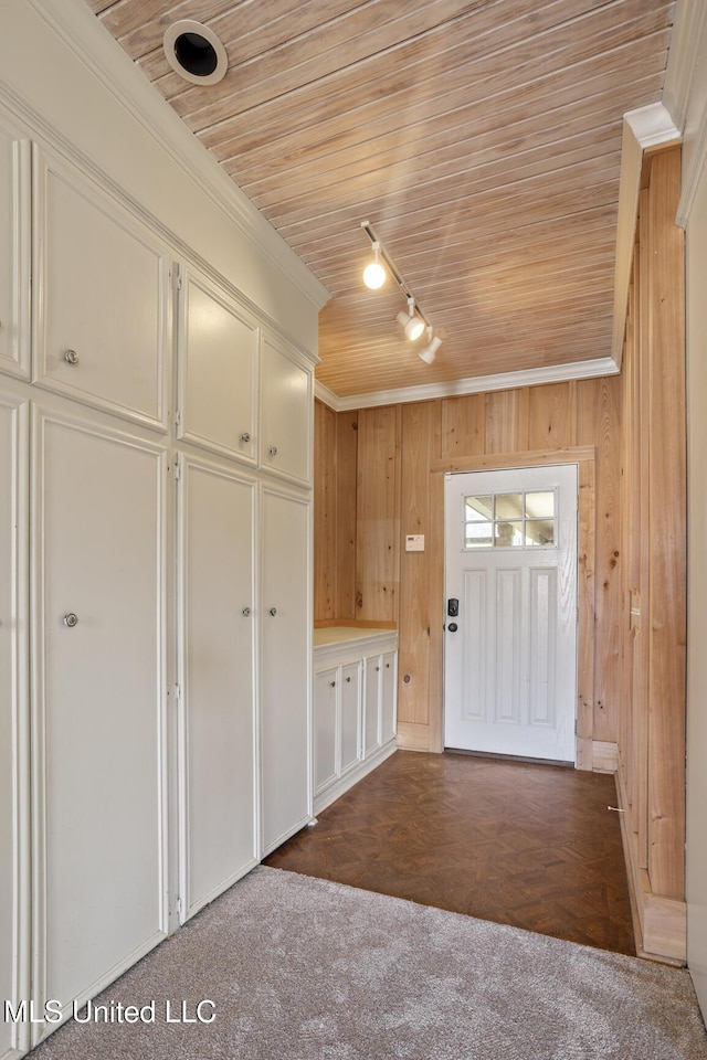 entrance foyer with track lighting, wooden ceiling, crown molding, and wood walls