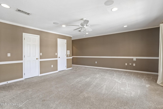 carpeted empty room featuring visible vents, baseboards, crown molding, and ceiling fan