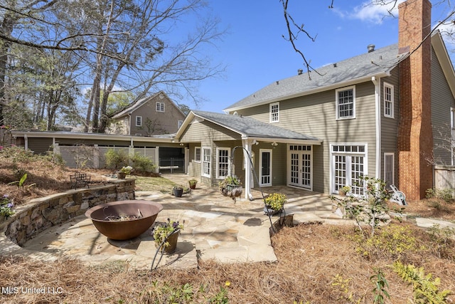 back of house featuring a patio, french doors, a fire pit, a sunroom, and a chimney