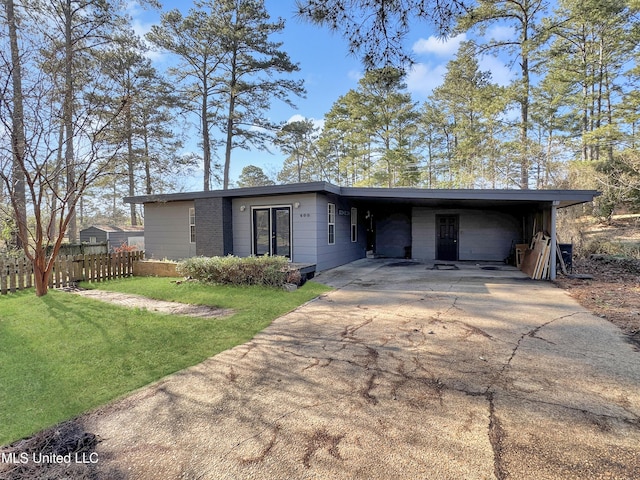 mid-century home featuring a carport, driveway, a front yard, and fence