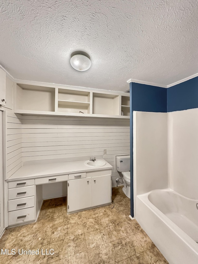 full bathroom featuring a textured ceiling, toilet, a tub to relax in, and a sink