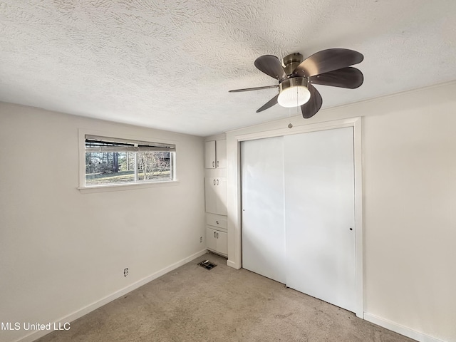 unfurnished bedroom featuring visible vents, baseboards, light colored carpet, a closet, and a textured ceiling