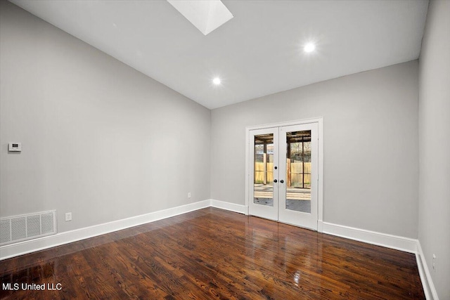 empty room featuring vaulted ceiling with skylight, french doors, and dark hardwood / wood-style floors